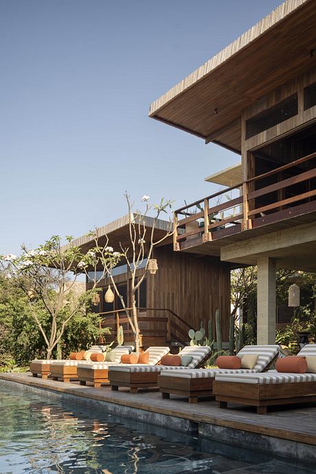 Wooden pavilion with pool, modern rustic decor and tropical foliage.