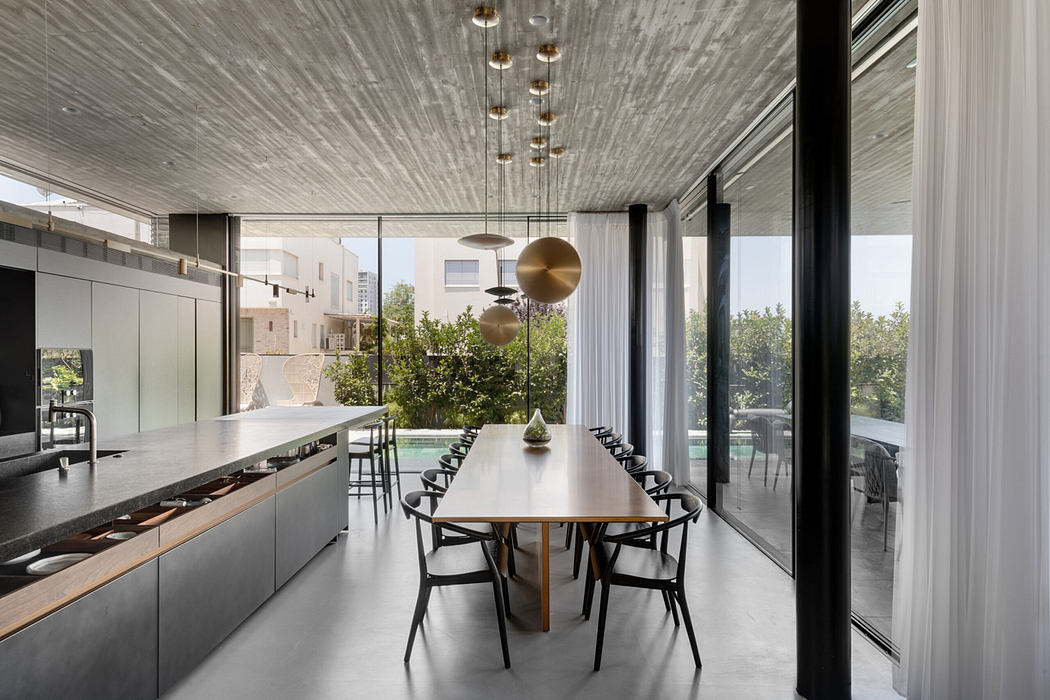 A modern, open-concept dining area with a large wooden table, sleek black chairs, and pendant lighting.