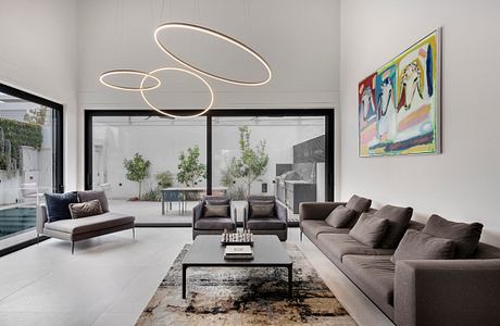 Modern, minimalist living room with sleek furniture, dramatic lighting fixtures, and abstract artwork.