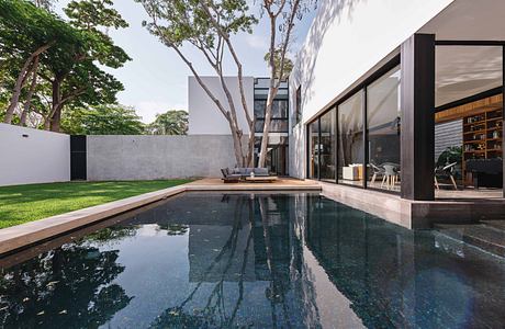 Modern residential architecture with a sleek glass exterior, private swimming pool, and lush landscaping.