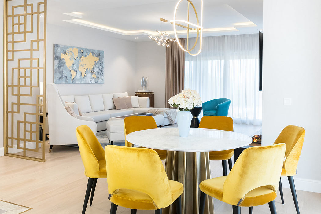 Opulent dining space with modern light fixtures, gray and yellow furnishings, and a world map artwork.