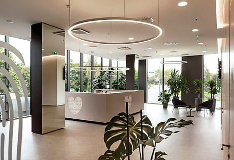 Sleek, modern lobby with circular lights, lush plants, and minimalist seating.