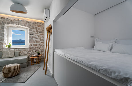 Cozy bedroom in stone cottage with window overlooking scenic landscape.