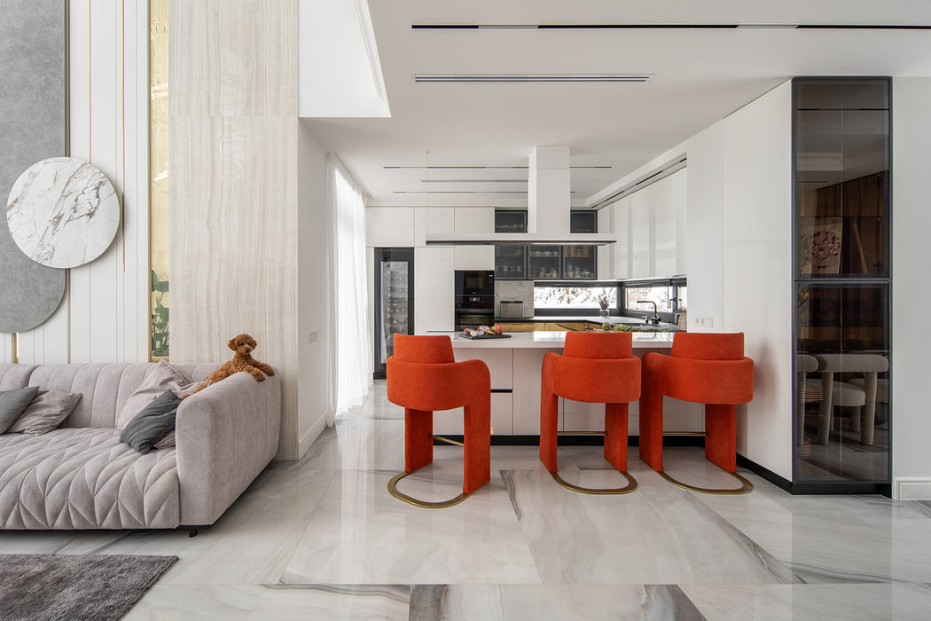 Sleek, modern kitchen with orange bar stools, marble accents, and open living space.
