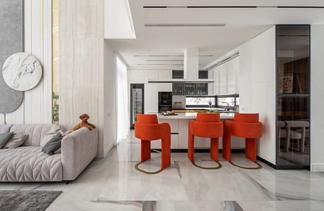 Sleek, modern kitchen with orange bar stools, marble accents, and open living space.