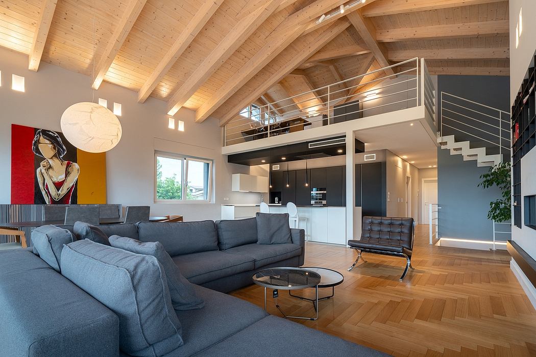 Modern loft-style interior with wooden beams, gray sofas, and raised platform.