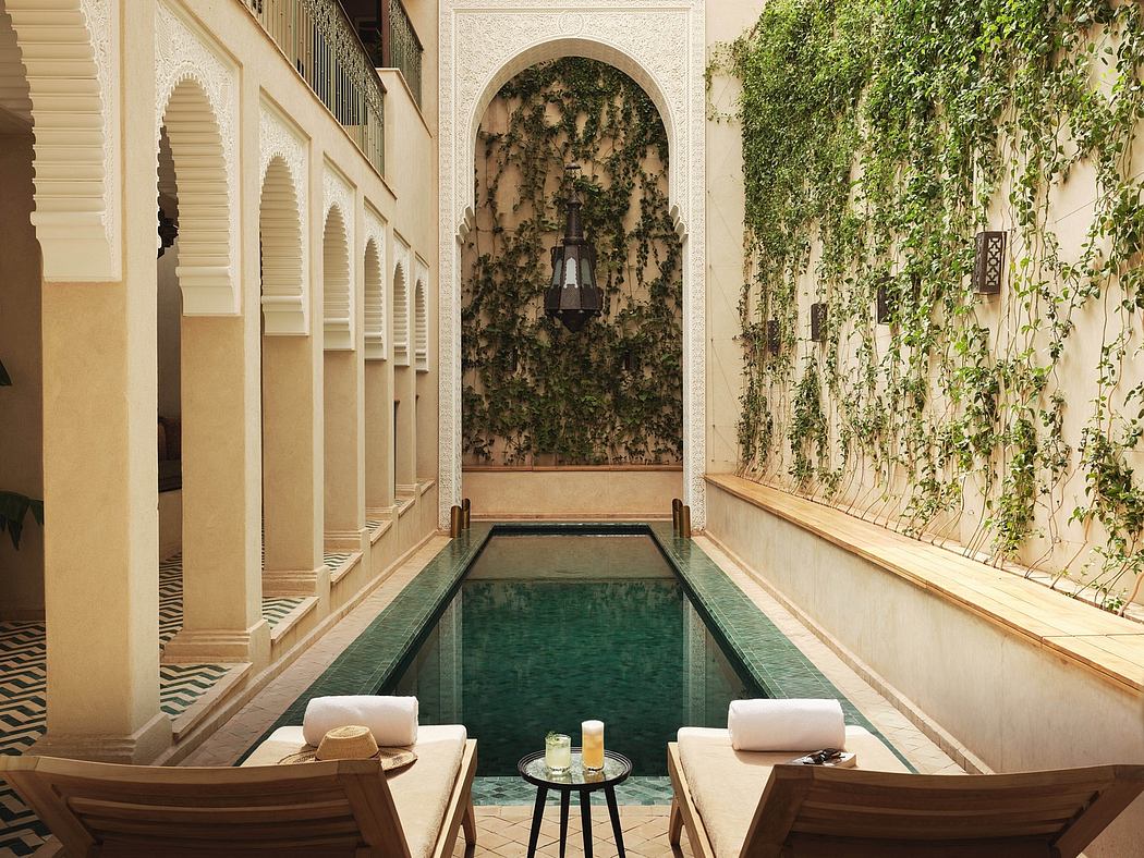 An ornate Moroccan-style indoor pool surrounded by lush greenery and intricate architectural details.