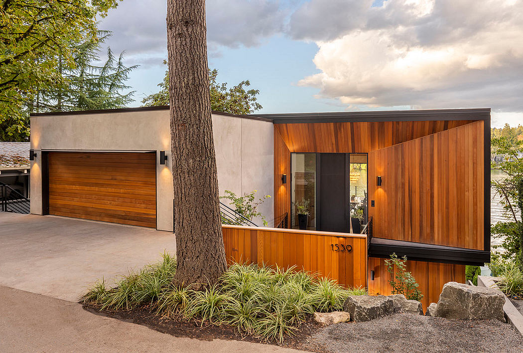 Modern wooden-clad home with concrete accents, large windows, and lush landscaping.