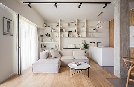 Modern and minimalist living room with built-in shelves, comfortable sofa, and concrete column.