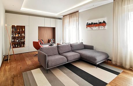 A modern living room with a gray sectional sofa, wall storage unit, and abstract artwork.