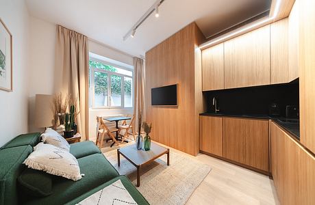 A cozy living area with modern wood paneling, a green sofa, and a dining nook by the window.