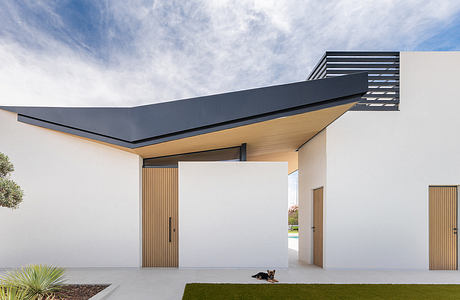 Modern architectural design with striking cantilevered roof, wooden accents, and lawn landscaping.