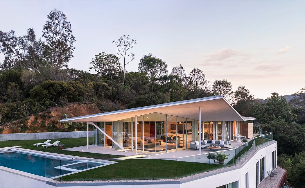 A modern, open-concept house with a glass-walled living area and an outdoor pool surrounded by a lush landscape.