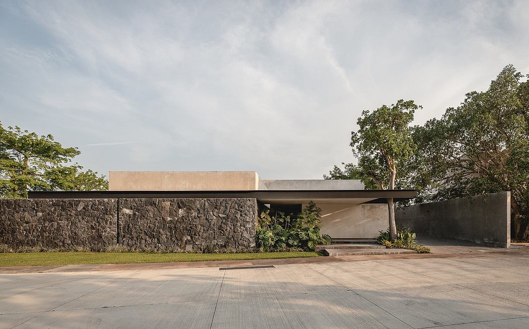 Modern architectural design with stone walls, overhanging roof, and lush greenery.