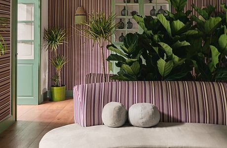 A vibrant, nature-inspired interior design with plush seating, greenery, and bold color accents.