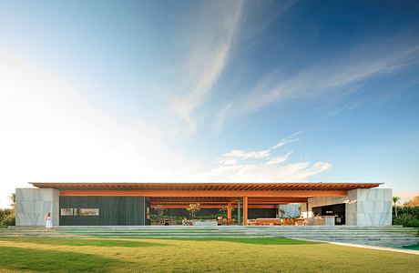 Sleek, modern home with expansive outdoor living space, wooden beams, and lush green lawn.