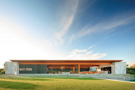 Sleek, modern home with expansive outdoor living space, wooden beams, and lush green lawn.