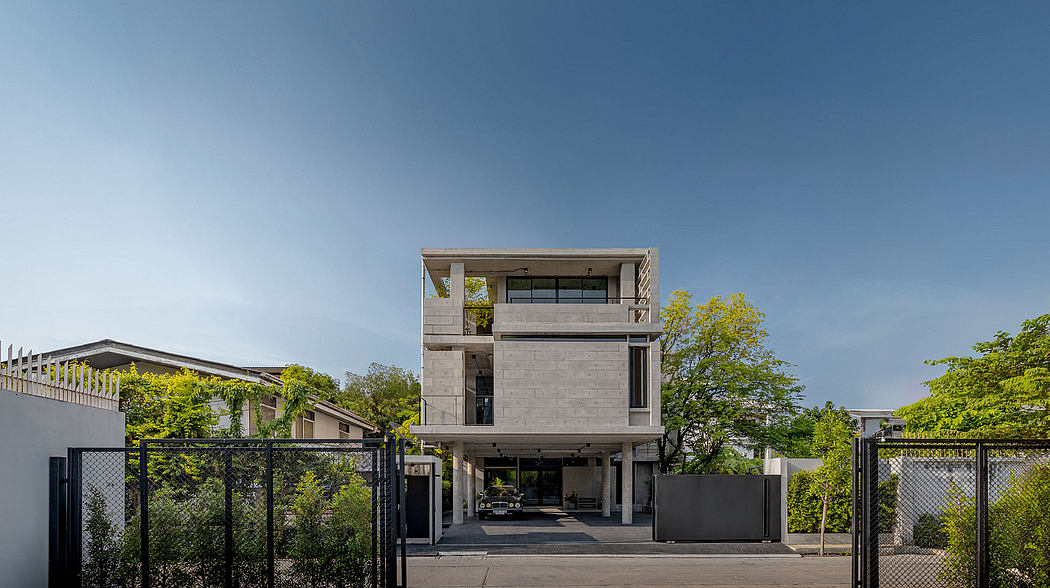 A modern, three-story concrete building with a covered garage and lush greenery.