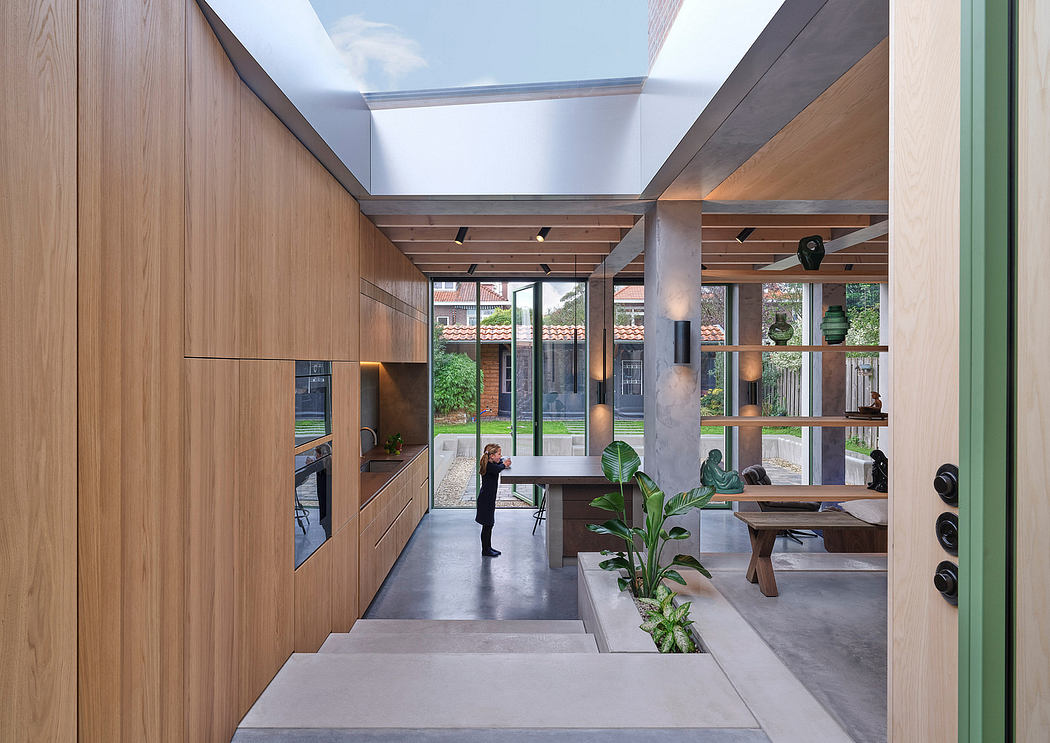 A spacious, modern interior with wooden panels, concrete floors, and lush foliage.