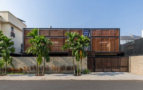 Modern tropical architectural design with wooden louvers and palm trees.