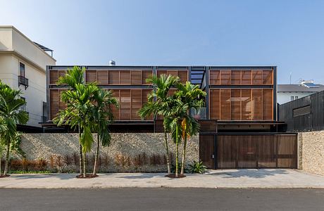 Modern tropical architectural design with wooden louvers and palm trees.