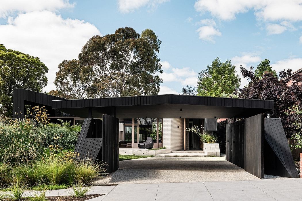 Modern black wood and glass structure with a covered walkway and lush greenery.