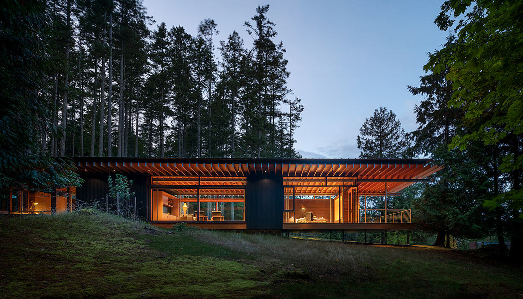A modern, wooden structure nestled in a forested landscape, featuring large windows and a cantilevered roofline.