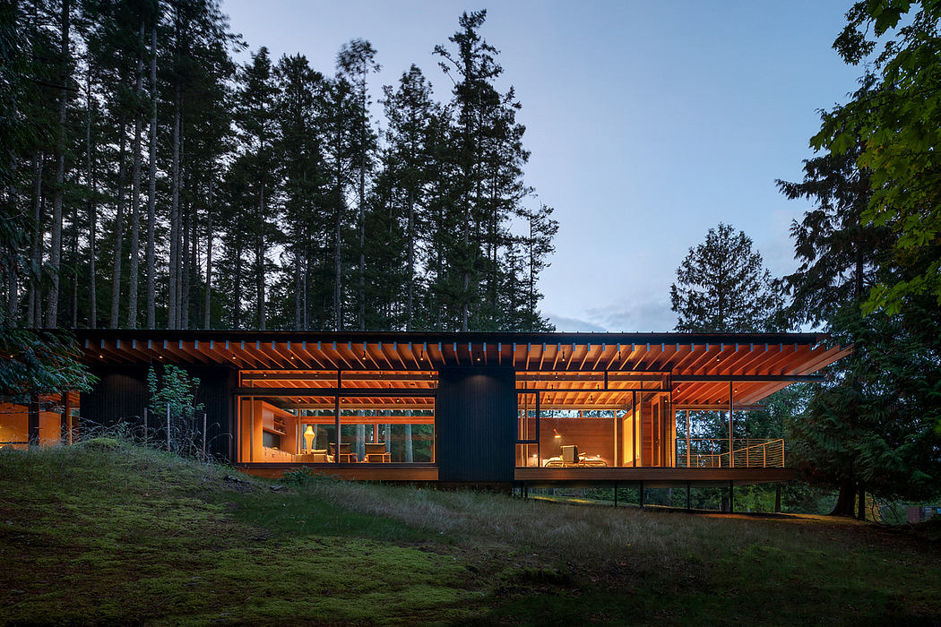 A modern, wooden structure nestled in a forested landscape, featuring large windows and a cantilevered roofline.