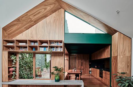 Striking wood-paneled interior with built-in shelving, large windows, and plants.
