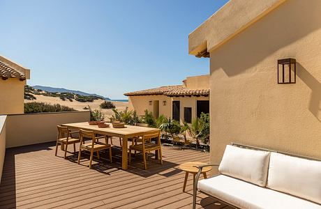 Warm-toned stucco exterior with tiled roof, wooden deck, and minimalist furnishings.