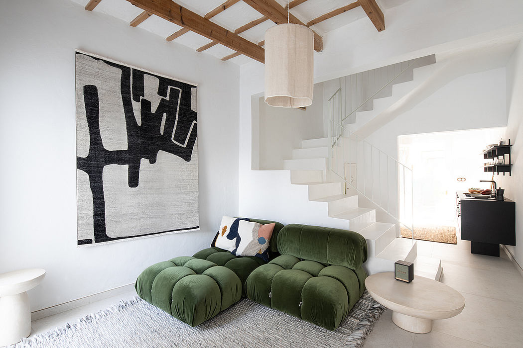 Spacious living room with white walls, exposed wood beams, and a modern green sectional.
