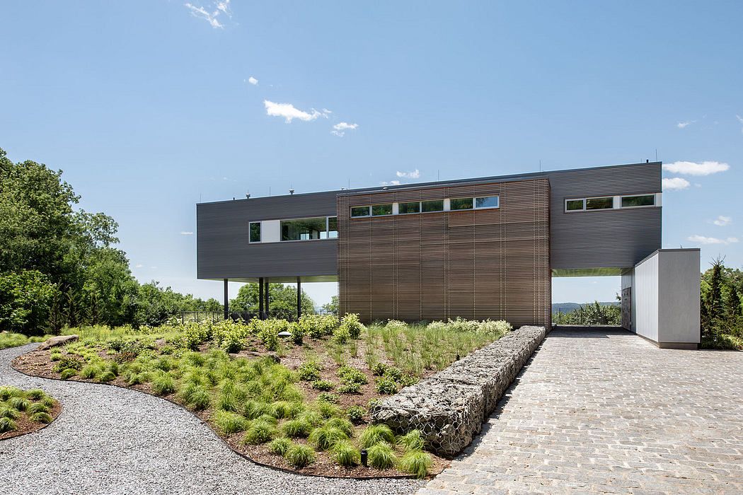 A modern, minimalist building with a wooden facade, surrounded by a landscaped garden.
