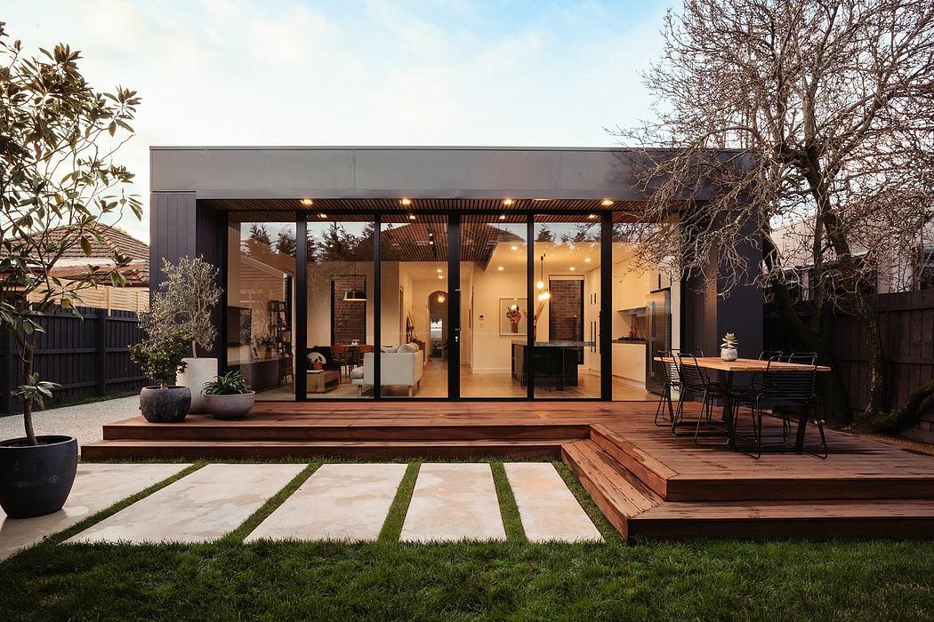 Sleek modern structure with expansive glass walls, wooden deck, and landscaped yard.