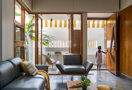 A cozy living room with modern furniture, wood accents, and tropical plants.