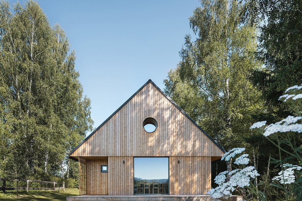 A modern wooden cabin nestled in a lush forest, with large windows framing the scenic view.
