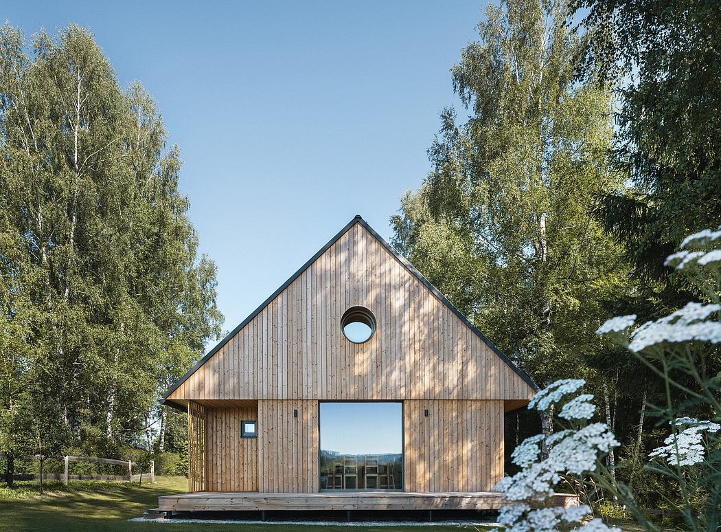 A modern wooden cabin nestled in a lush forest, with large windows framing the scenic view.