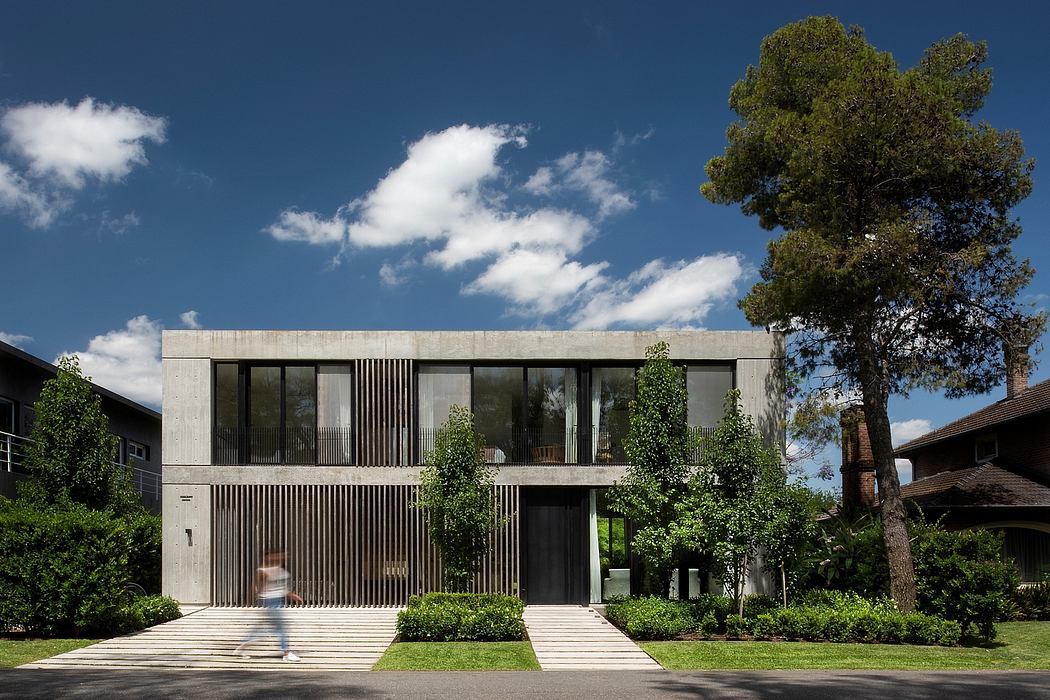 Sleek concrete exterior with vertical wooden slats, expansive windows, lush greenery.