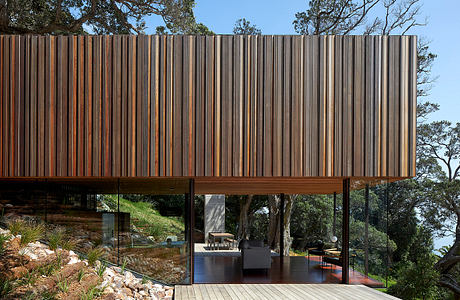 Wooden slatted facade with expansive glass walls and elevated outdoor terrace.