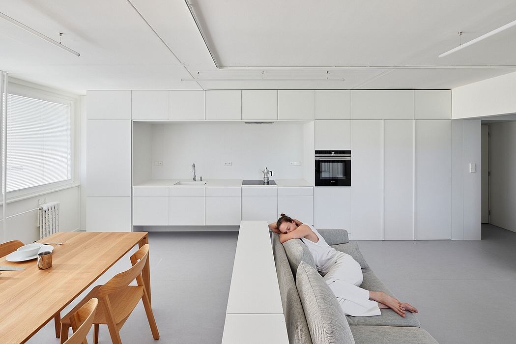 Minimalist open-concept kitchen and living area with sleek white cabinetry and modern furnishings.
