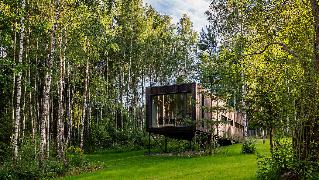 A modern, glass-enclosed treehouse nestled in a lush, forested environment.