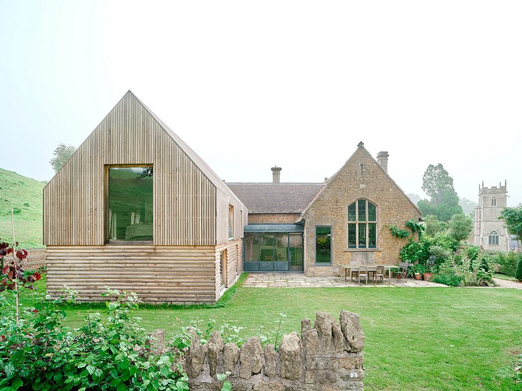 A modern wooden addition connected to a historic stone church building, surrounded by a lush garden.