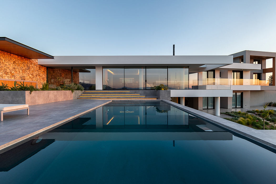 Sleek, modern architecture with expansive glass walls, pool, and lush landscaping.