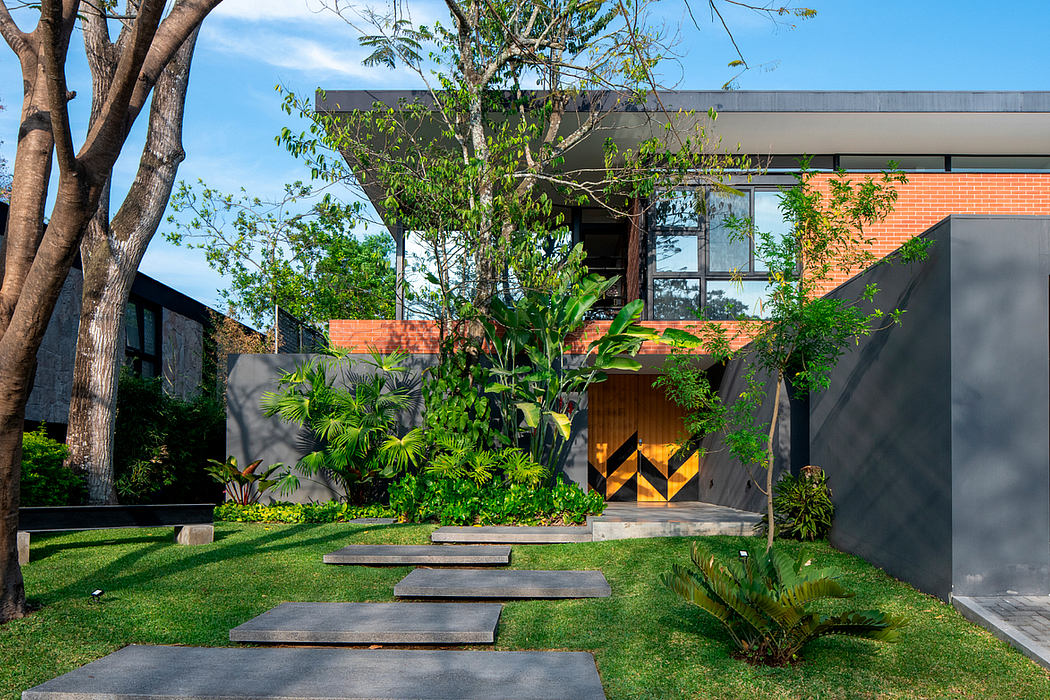 A modern, minimalist home design with lush, tropical landscaping and a bold, geometric entryway.