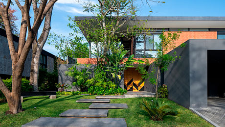 A modern, minimalist home design with lush, tropical landscaping and a bold, geometric entryway.