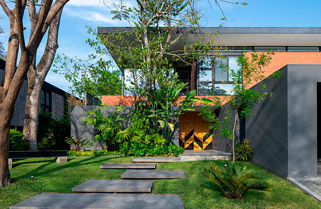 A modern, minimalist home design with lush, tropical landscaping and a bold, geometric entryway.