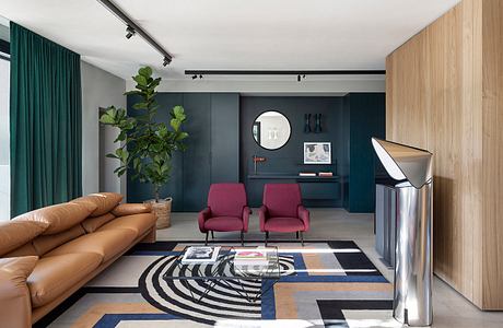 Cozy living room with modern furniture, vibrant colors, and geometric patterned rug.