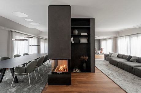 Modern, minimalist living space with sleek black fireplace unit, open floor plan, and natural materials.