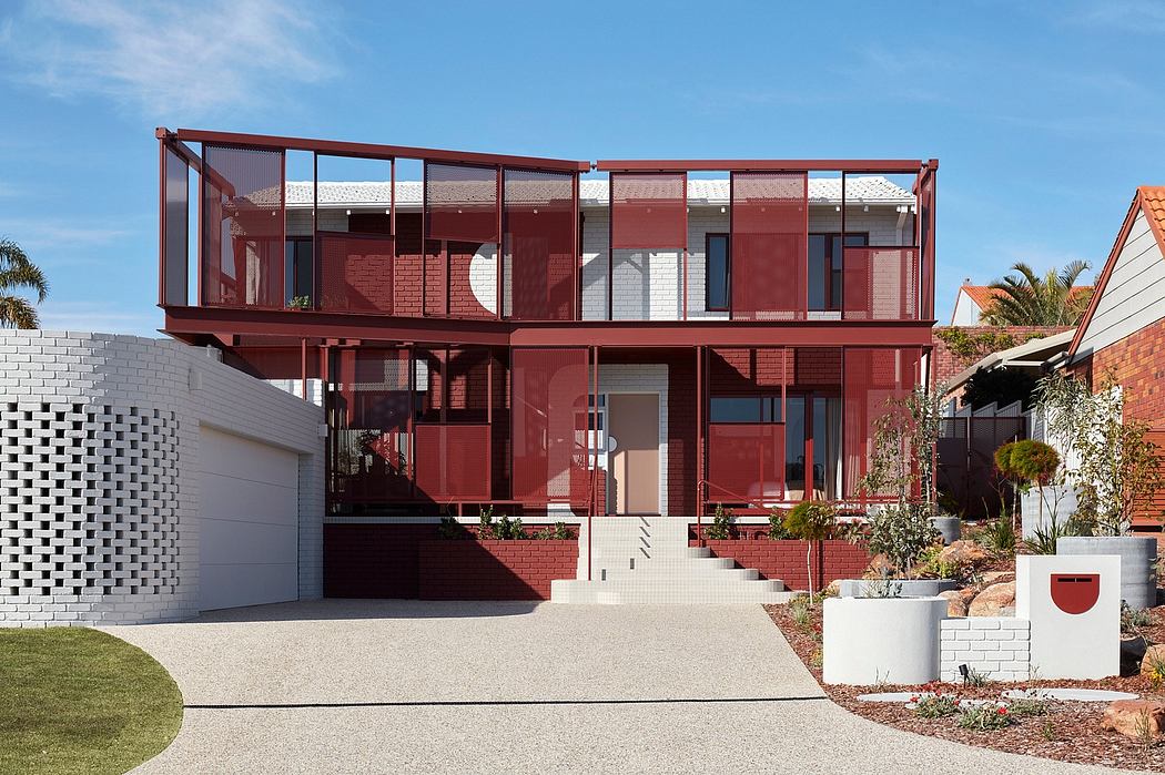 A striking two-story home with a distinctive red steel frame, brick walls, and expansive windows.
