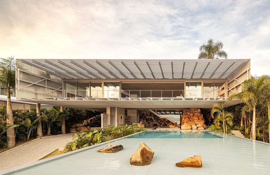 Expansive modern structure with sleek roof, balcony, and natural stone elements around pool.