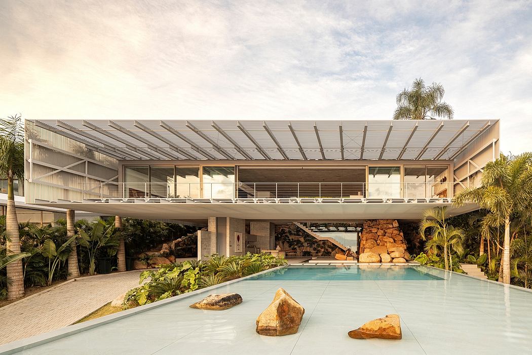 Expansive modern structure with sleek roof, balcony, and natural stone elements around pool.